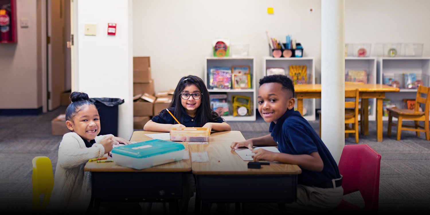 A group of happy students sits around the desk, working on their assignments.